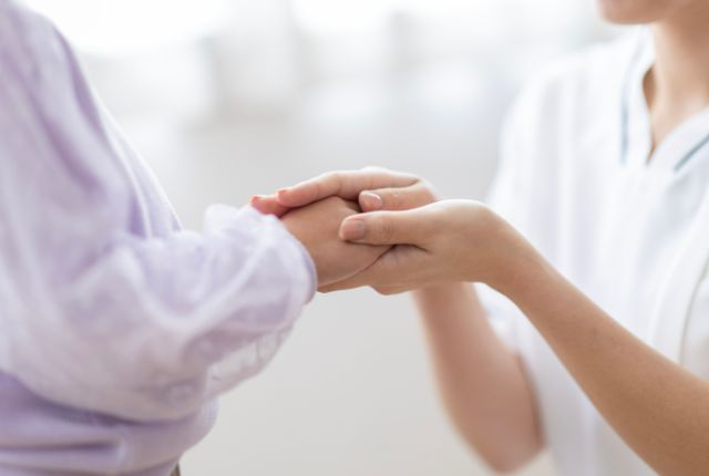 高齢女性の手を持つ看護師